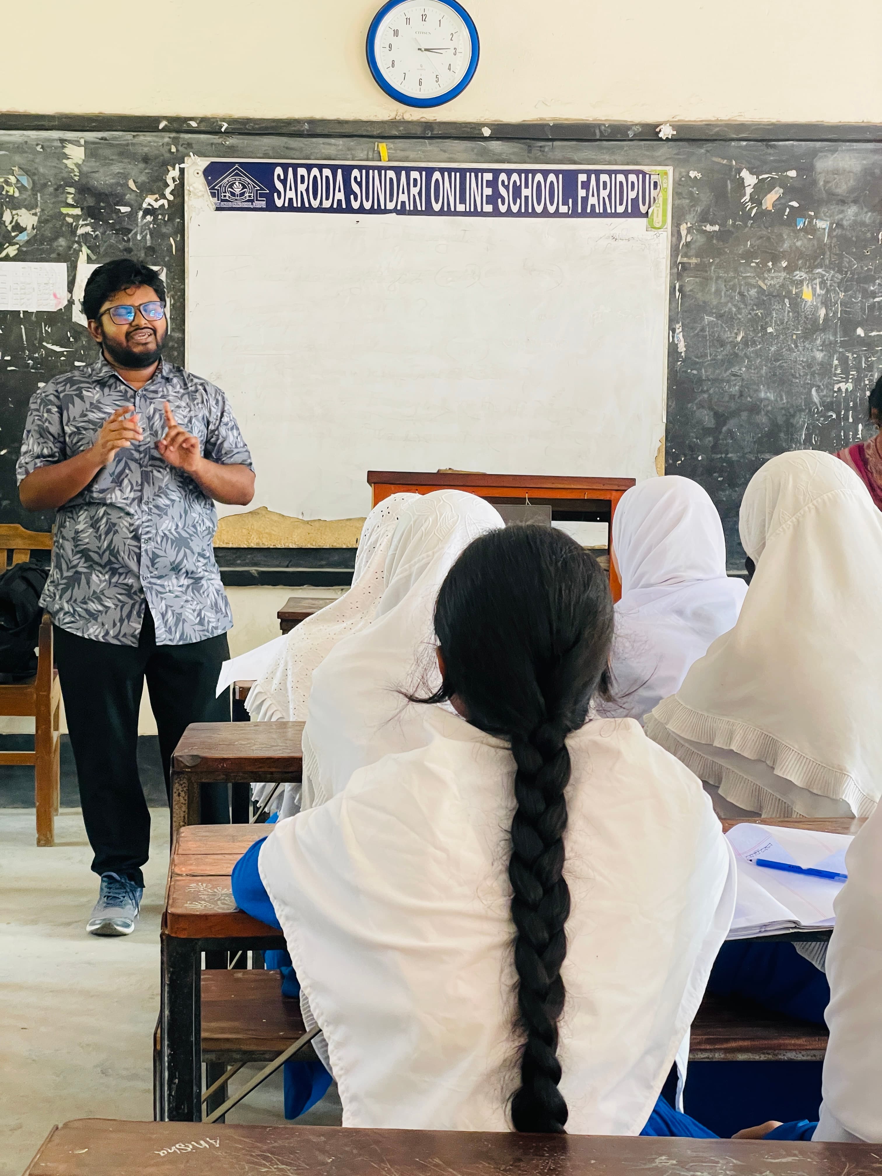 A volunteer speaking to students at Saroda Sundari Online School, Faridpur