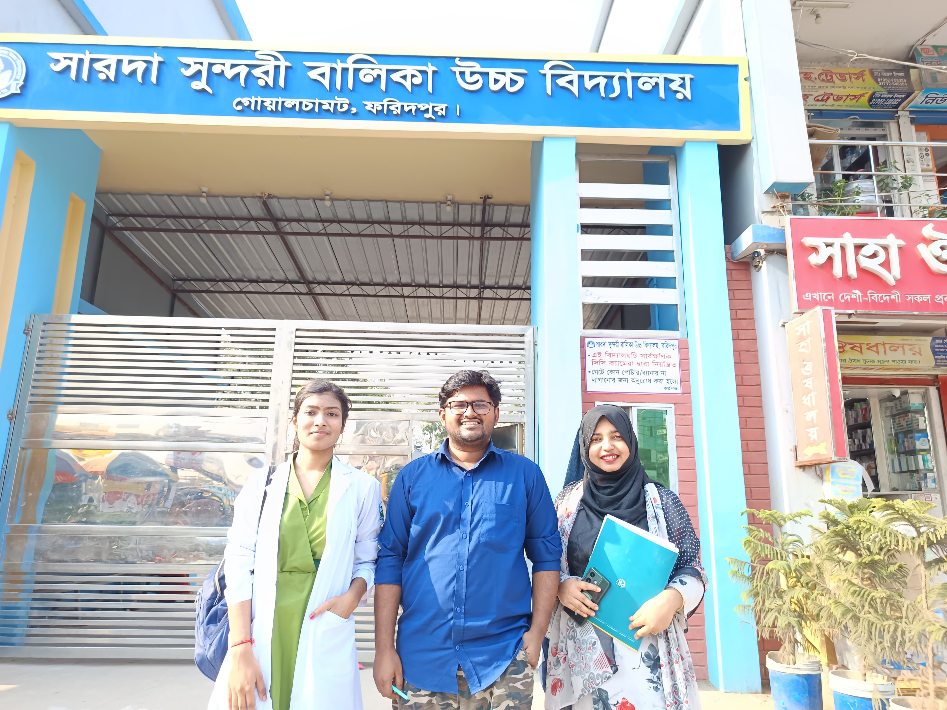 Three SoulConnect team members outside a school gate in Faridpur